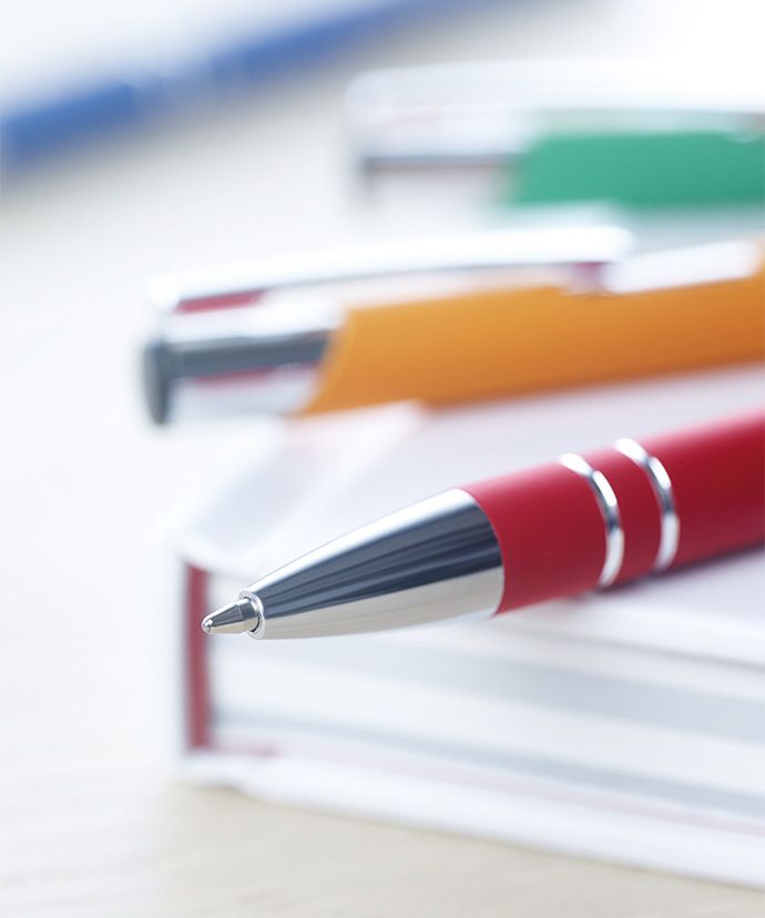 Des stylos en métal de différentes couleurs posés sur un livre