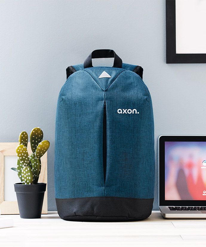 Sac à dos personnalisé bleu sur une table à côté d'un ordinateur portable et d'une plante. Objet publicitaire pour marketing interne.